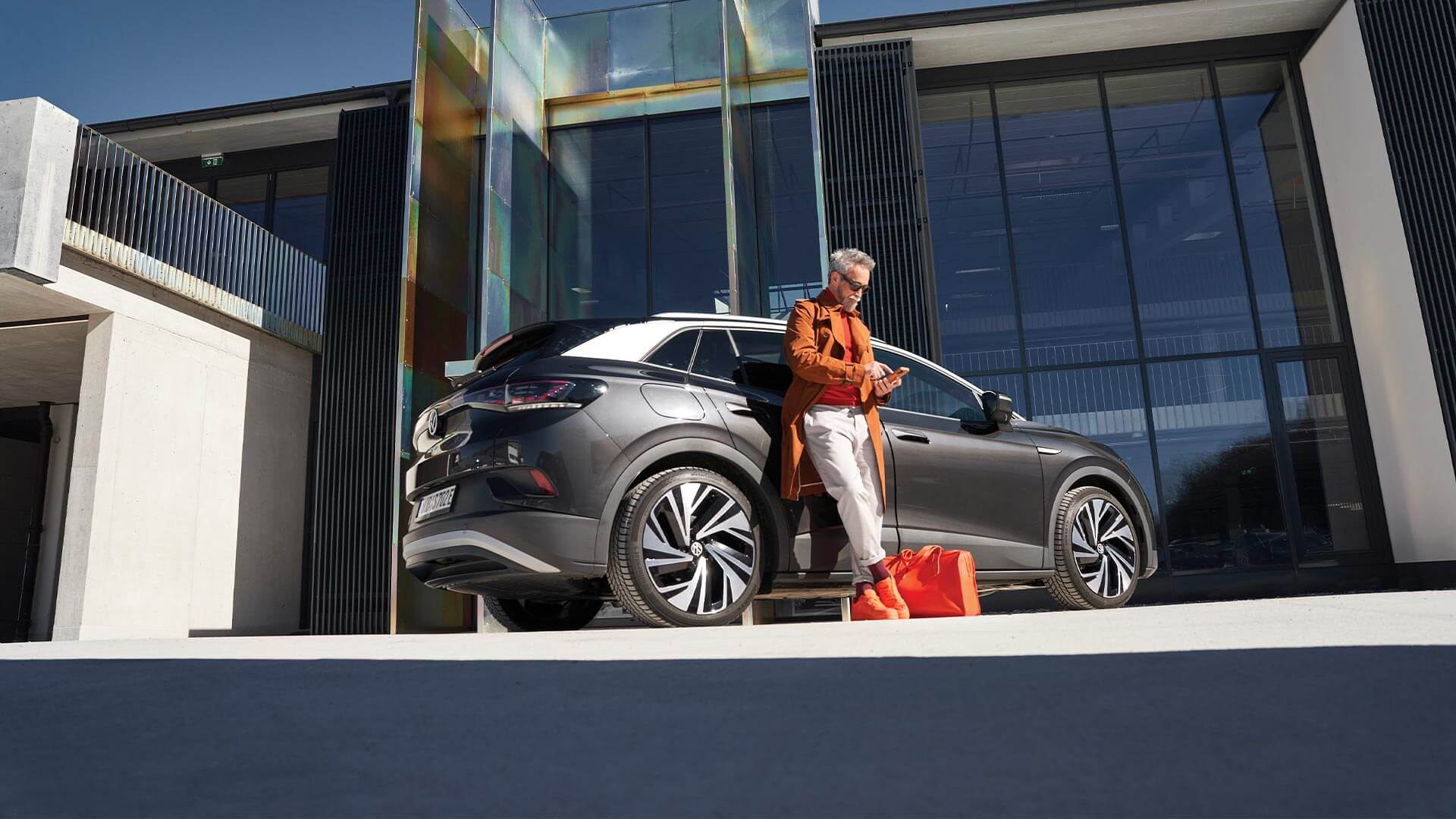 Uomo elegante che passeggia davanti alla Volkswagen Passat GTE per uso aziendale.